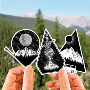 hands holding up a set of three illustrated mountain stickers